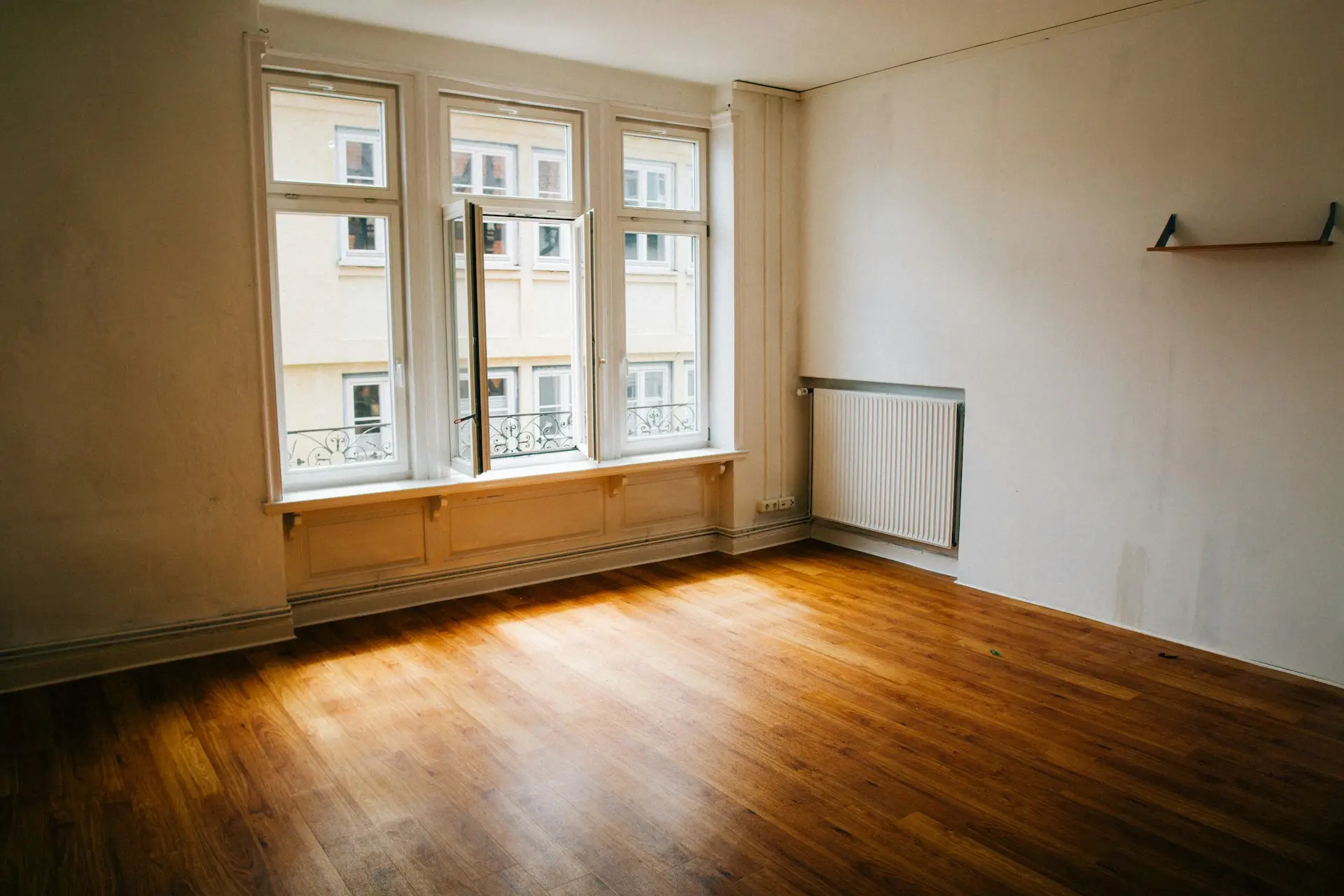 Helle, leere Altbauwohnung mit offenem Fenster und Holzboden
